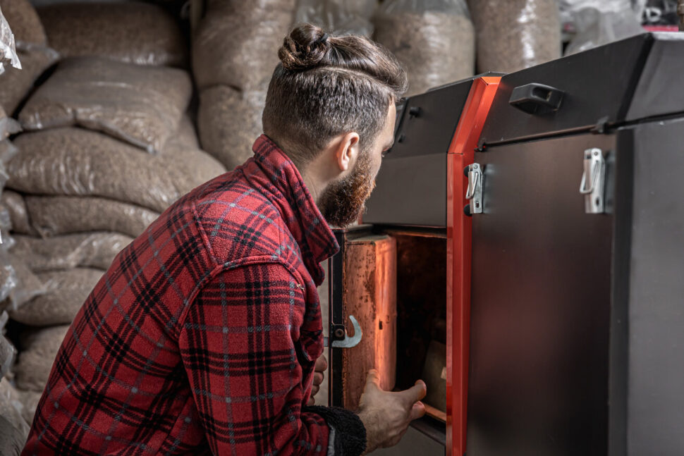 The young man with solid fuel boiler, working with biofuels, economical heating