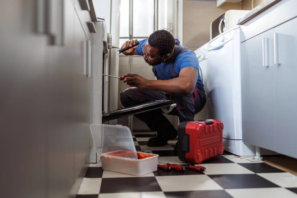 Technician repairing stove in a client's kitchen